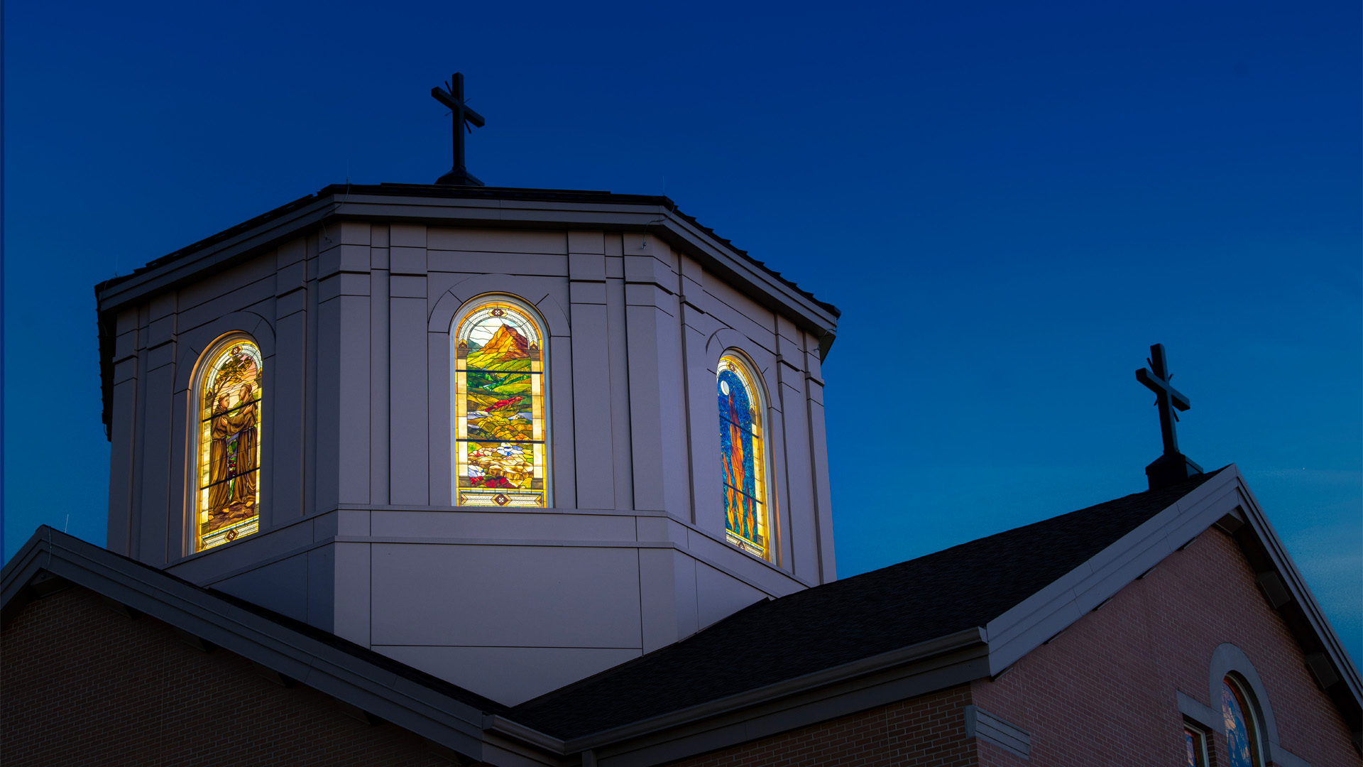 The University of Saint Francis Chapel of St Francis of Assisi at night with the stained glass windows lit up.