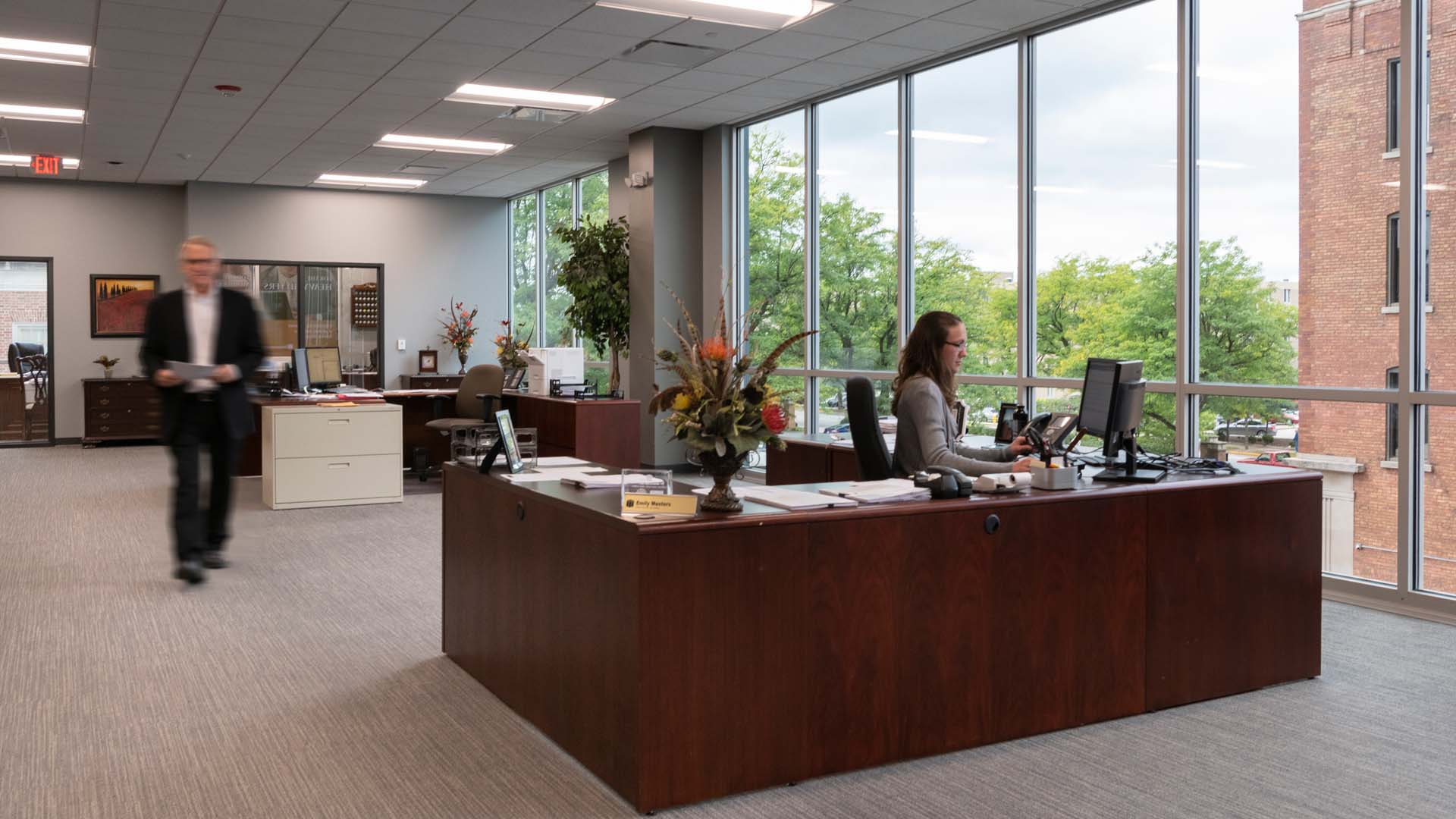 People working in the First Merchants Bank Office Space with wood desks and a large window.