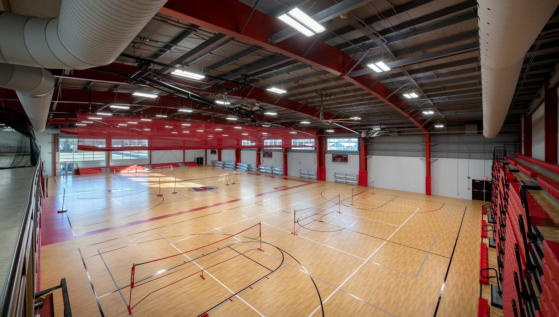 Adams Central Community School gym with an open ceiling and red accents.