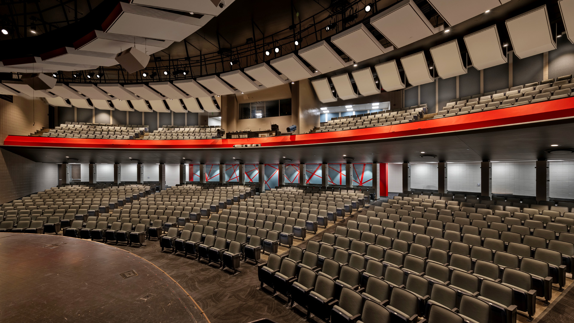 High school auditorium with balcony seating, branded bold red.