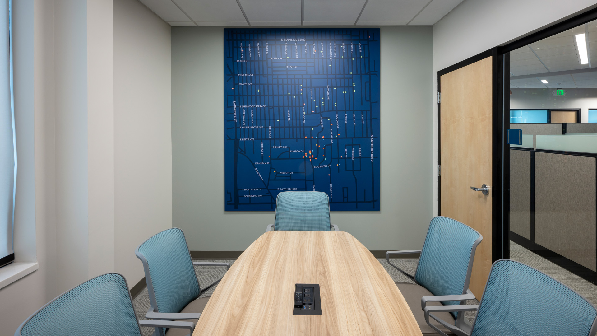 Conference room with blue city map, table, and blue chairs.