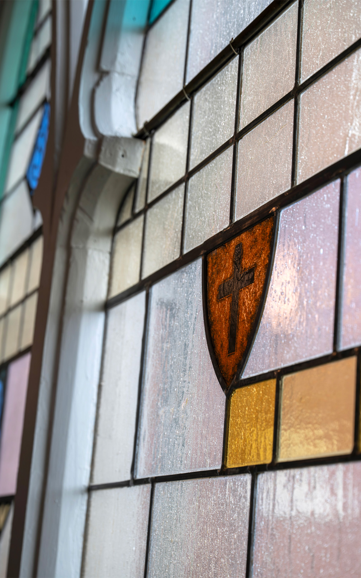 Stained glass window depicting a cross in St. Pauls Lutheran Church Heritage Hall.