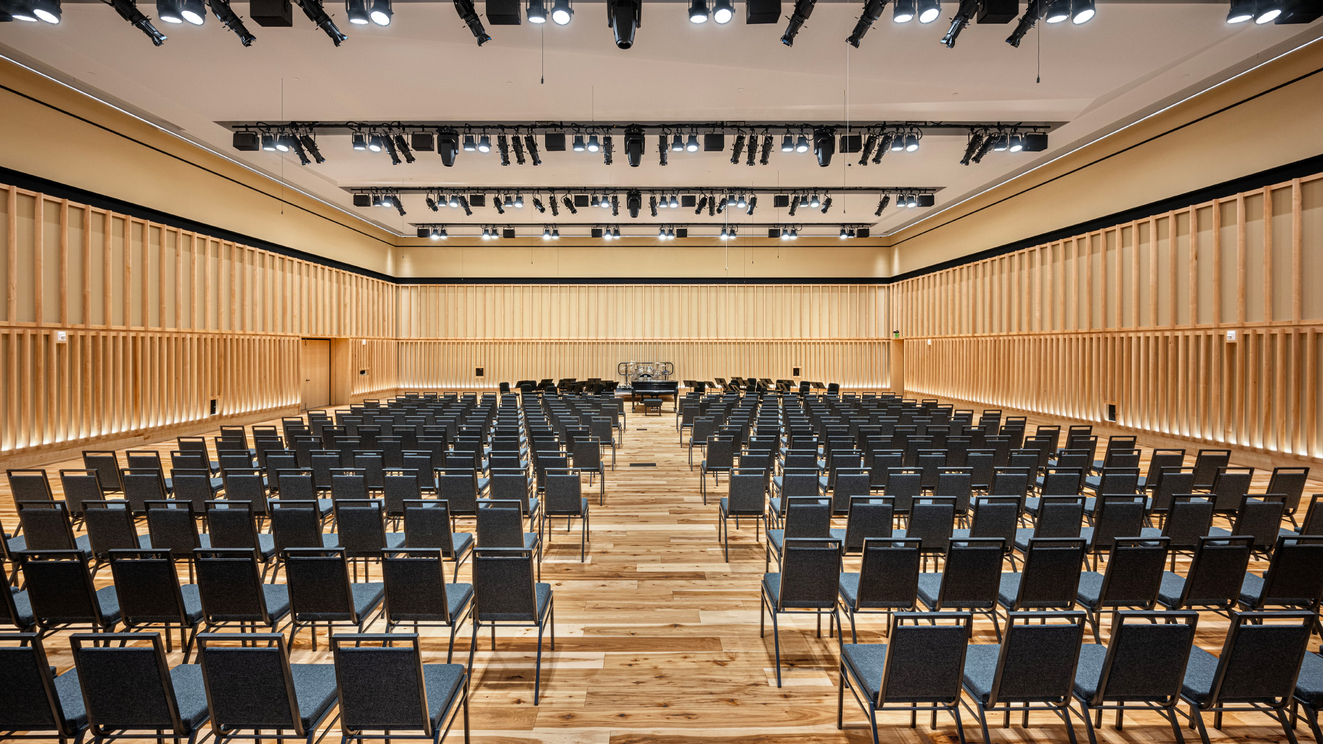 Auditorium performing arts center with unfixed seating and warm wood tones.