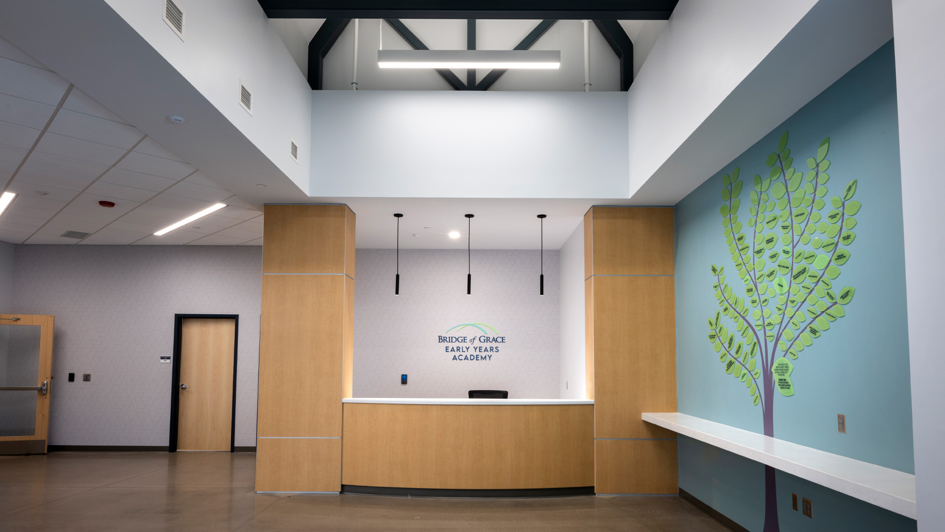 Lobby with wood desk and decorative tree graphic.