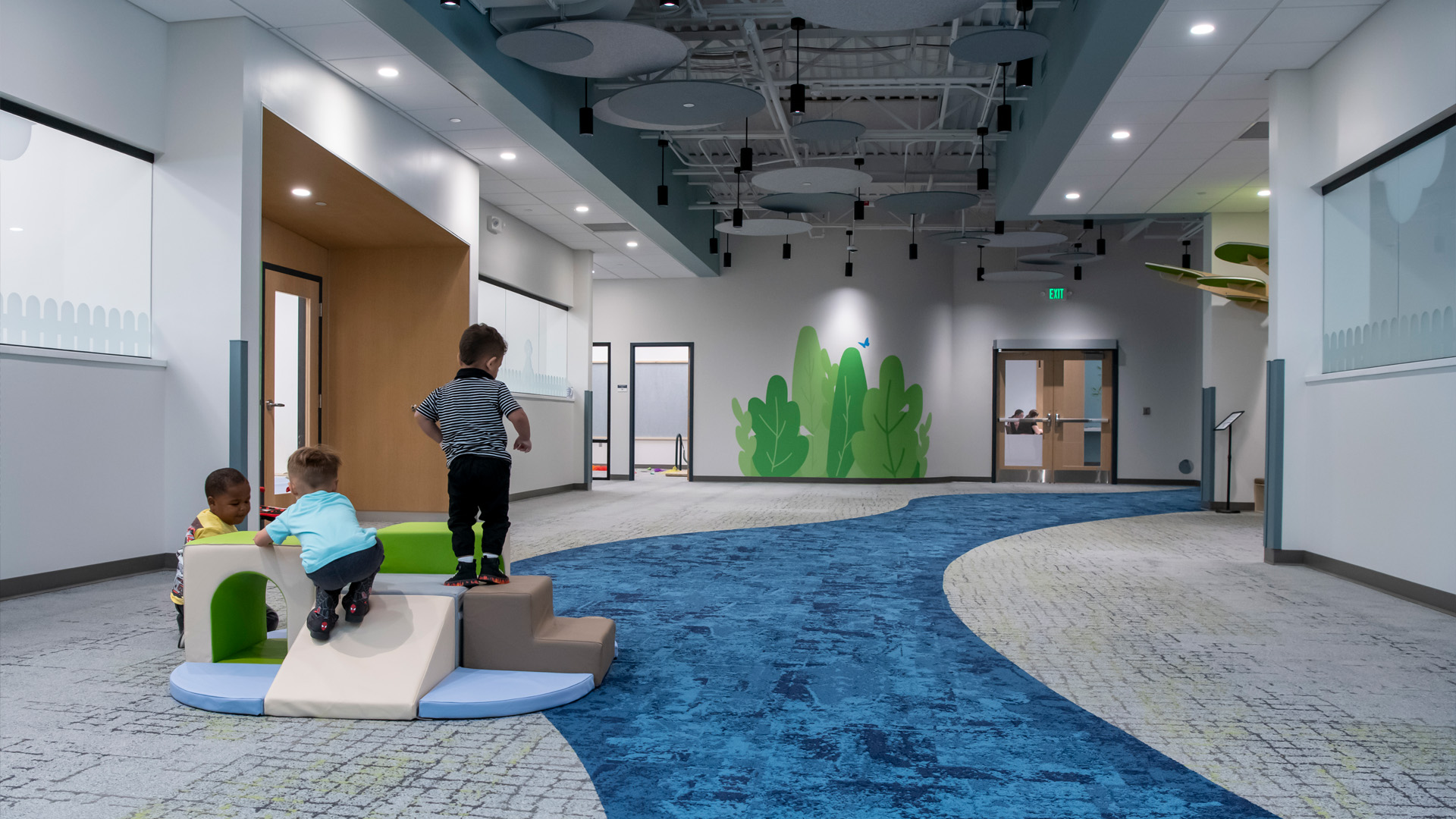 Children playing in welcoming lobby space with blue carpet and bright graphics.