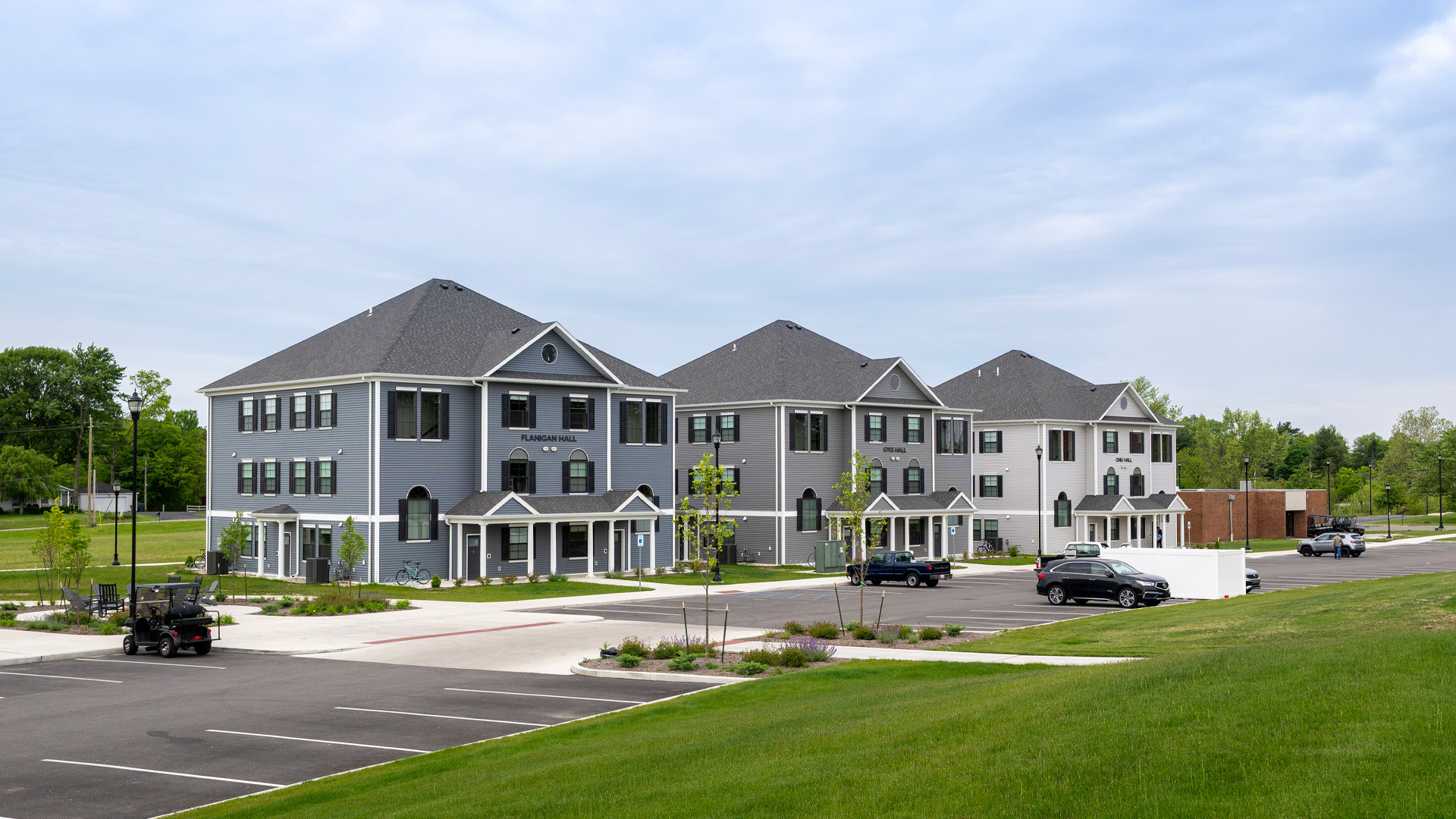 Three Taylor University residential village buildings with a parking lot in front.