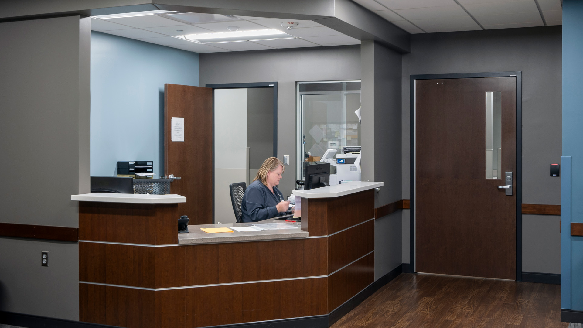 Secretary in healthcare facility working at front desk.