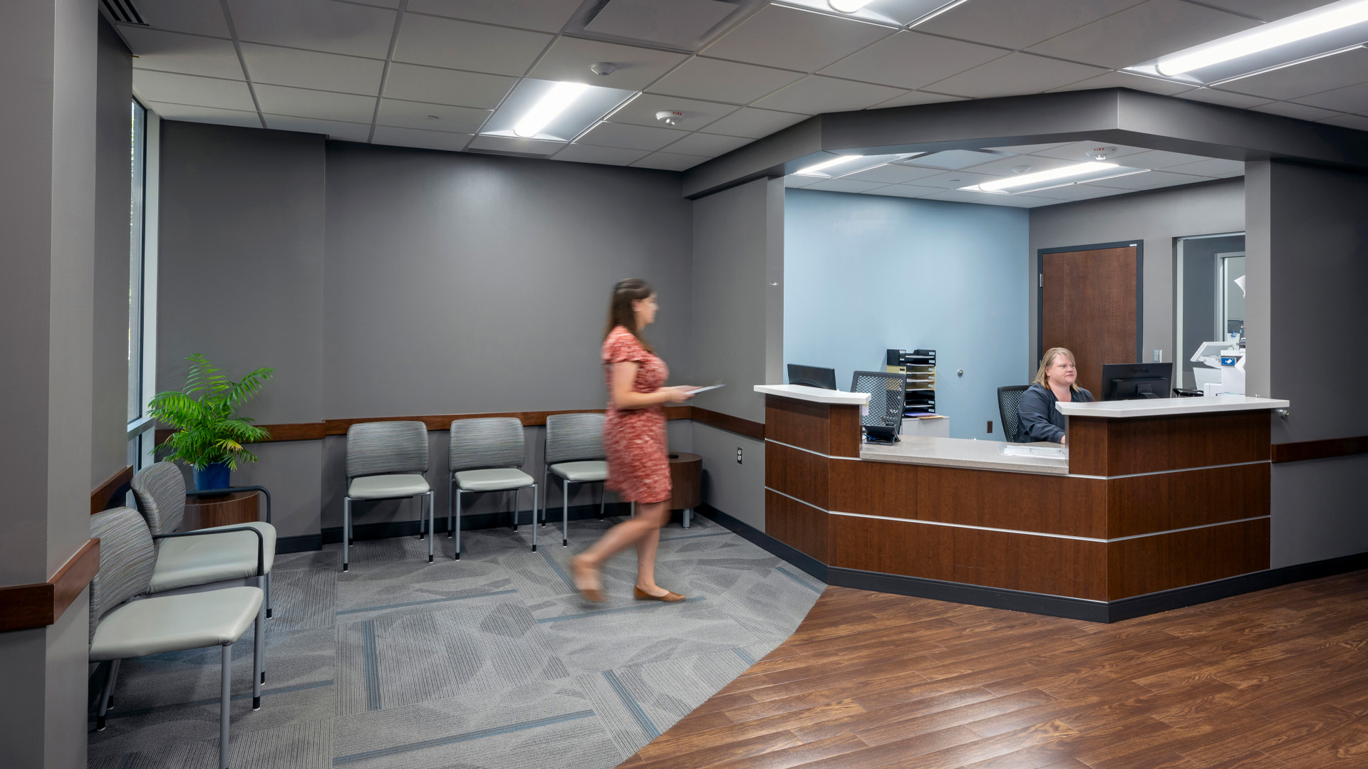 Patient turning in paperwork at healthcare front desk.