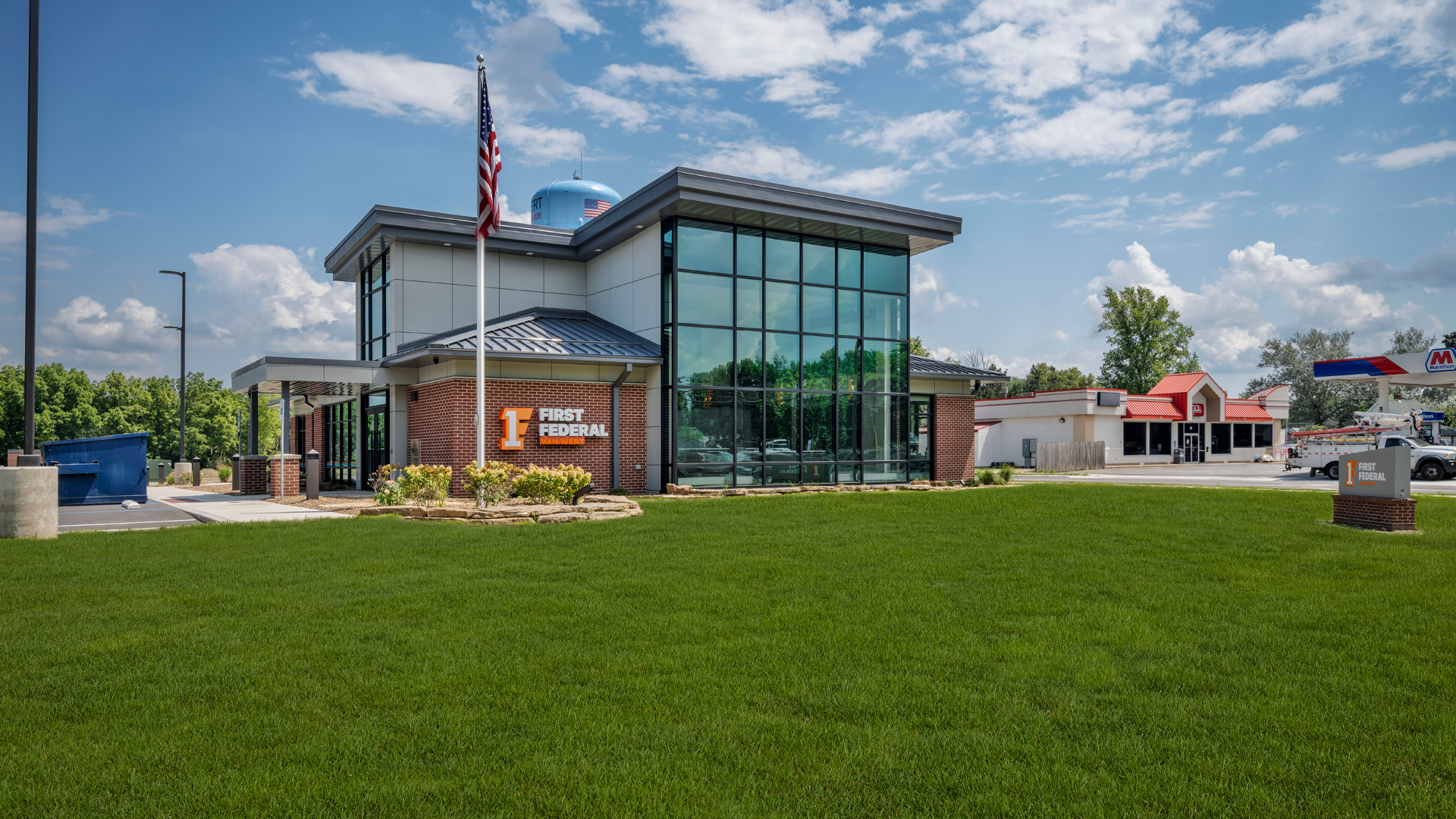 Bank branch exterior with large window wall and warm brick.