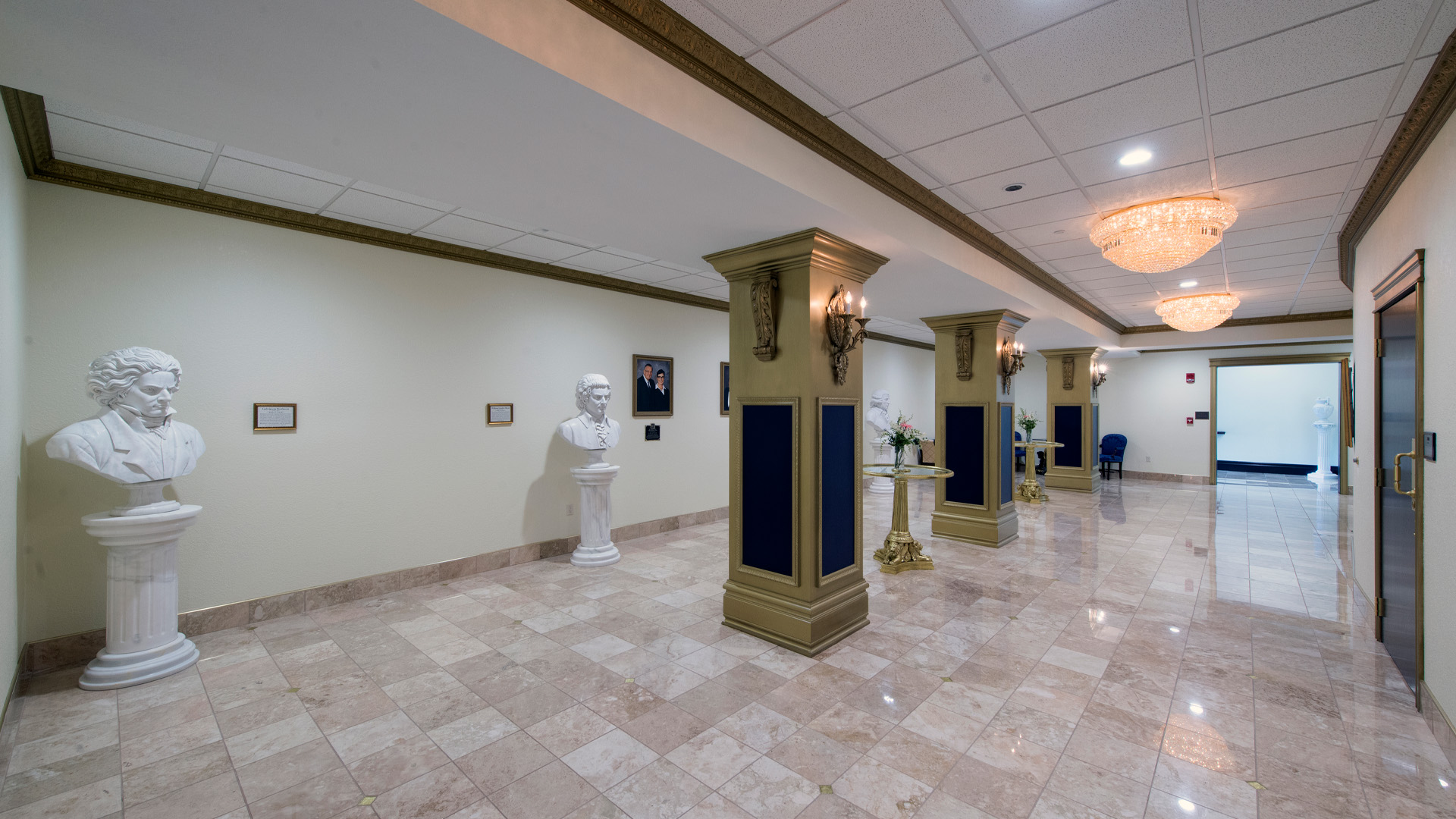 Trine University T Furth Performing Arts Center interior hallway with gold columns, white statues, and detailed lights.