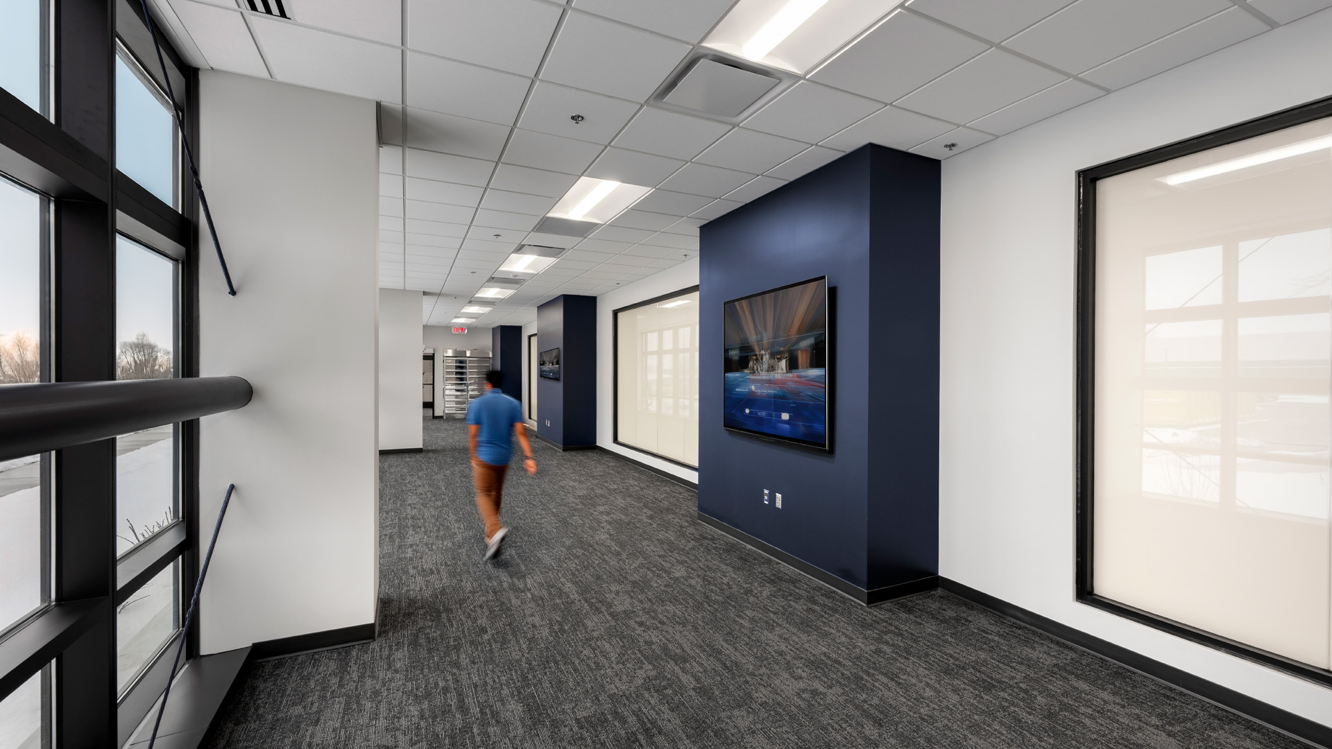 Walkway with person walking and internal branded tv.