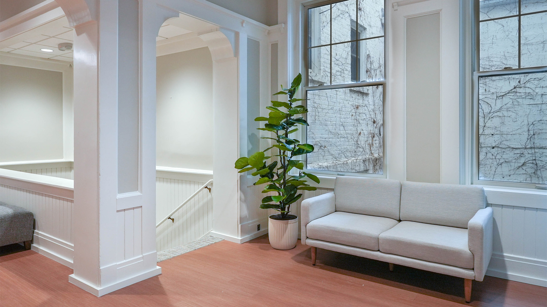 Cozy lobby area in Grace College's Westminster Hall with a gray couch and large windows.