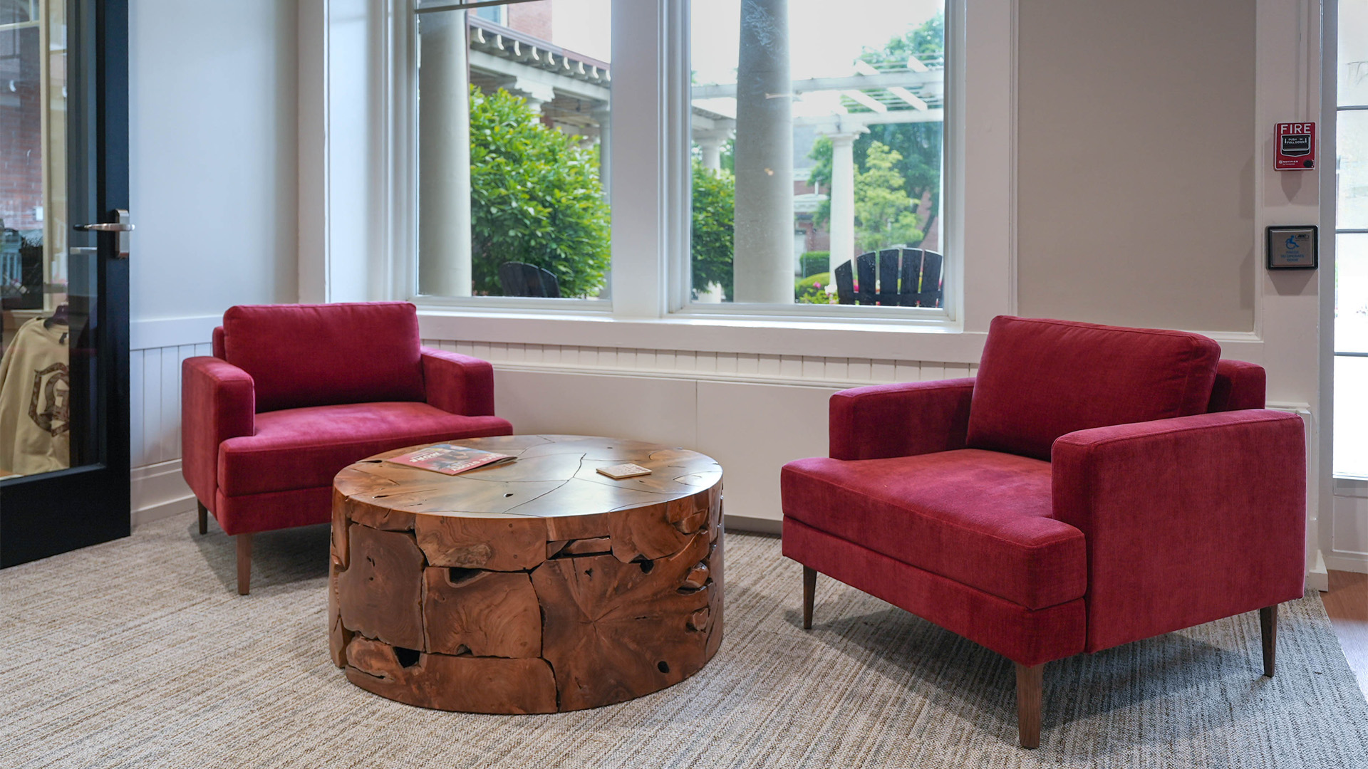 Cozy lobby area in Grace College's Westminster Hall with two red armchairs and a decorative wooden table.