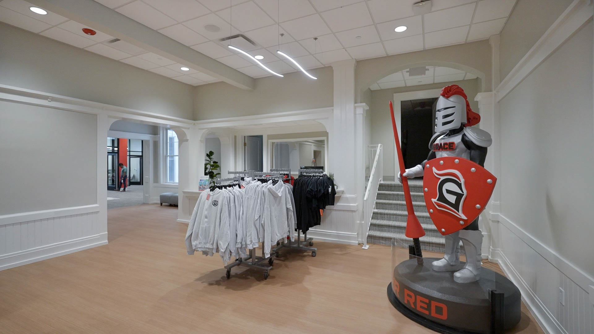 Grace Gear campus store in Grace College's Westminster Hall, with racks of clothes and the school mascot.