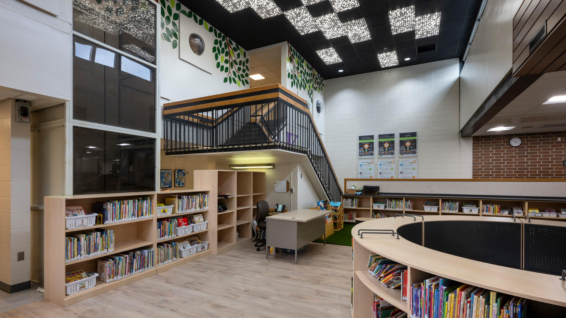 Early childhood library with detailed ceiling lighting, playful green elements, and circular library station.