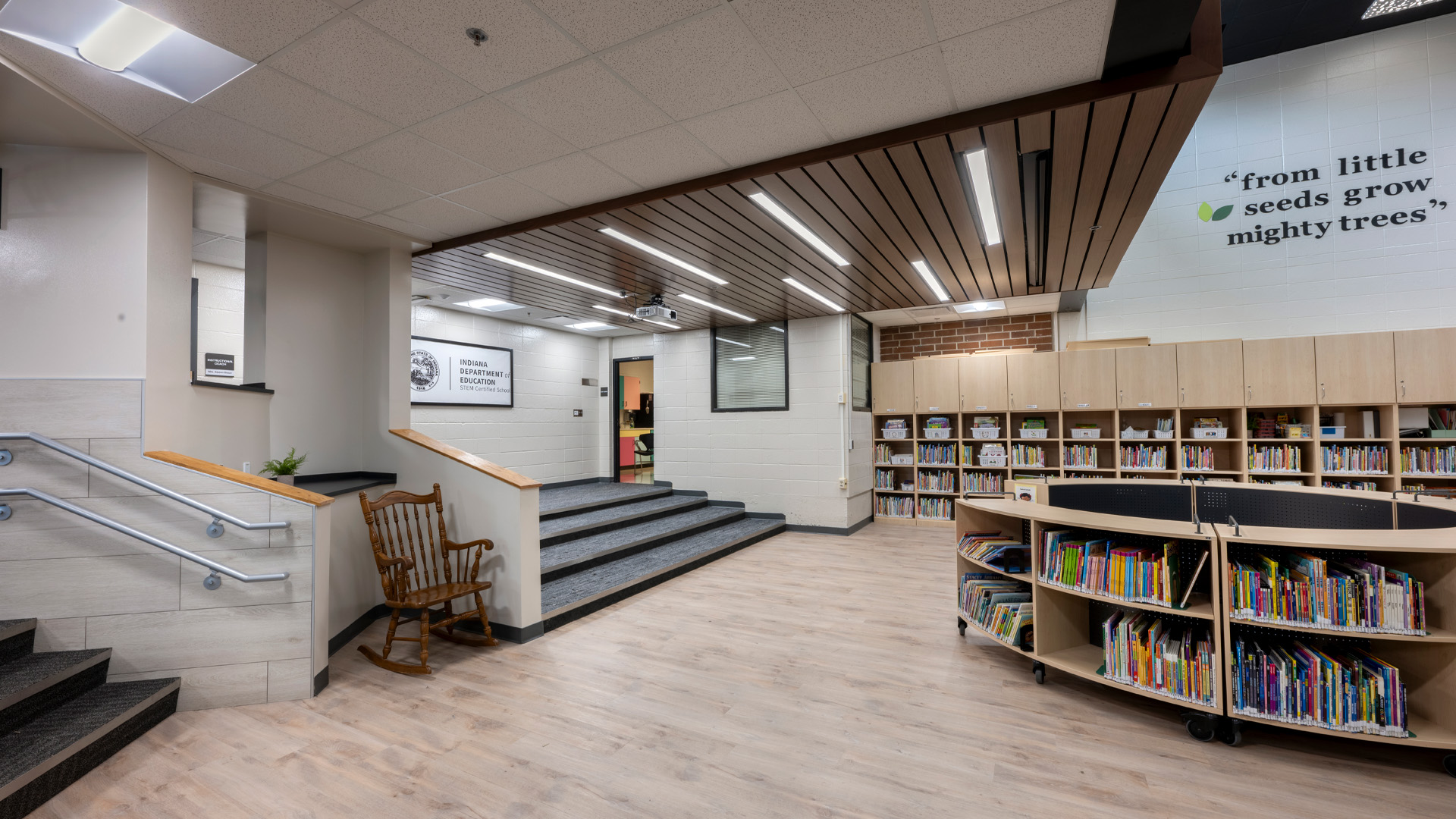 Early childhood library with detailed ceiling lighting, playful green elements, and circular library station.