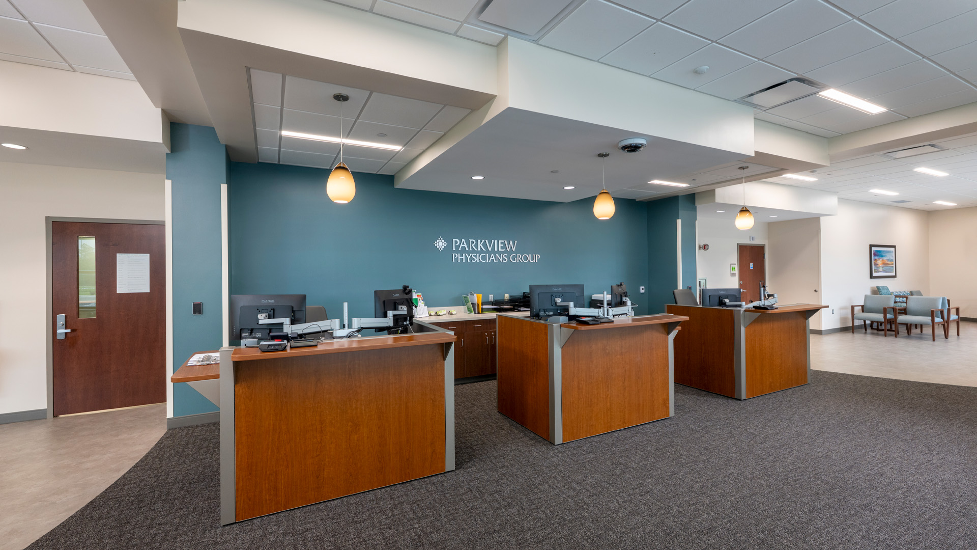 PPG Parkview Huntertown Clinic wood reception desks with a blue wall behind them.