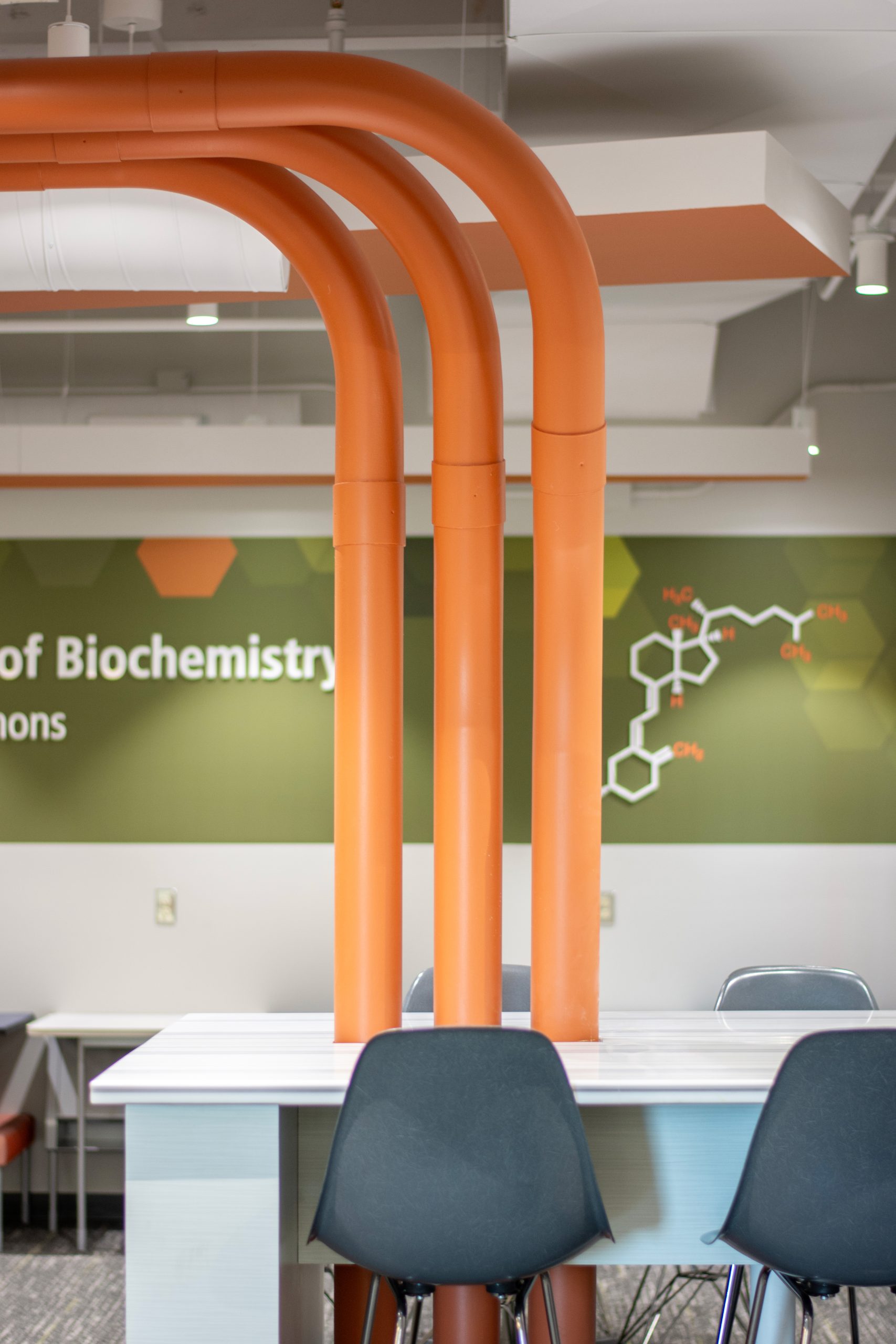 Bold orange pipes in chemistry space for students.
