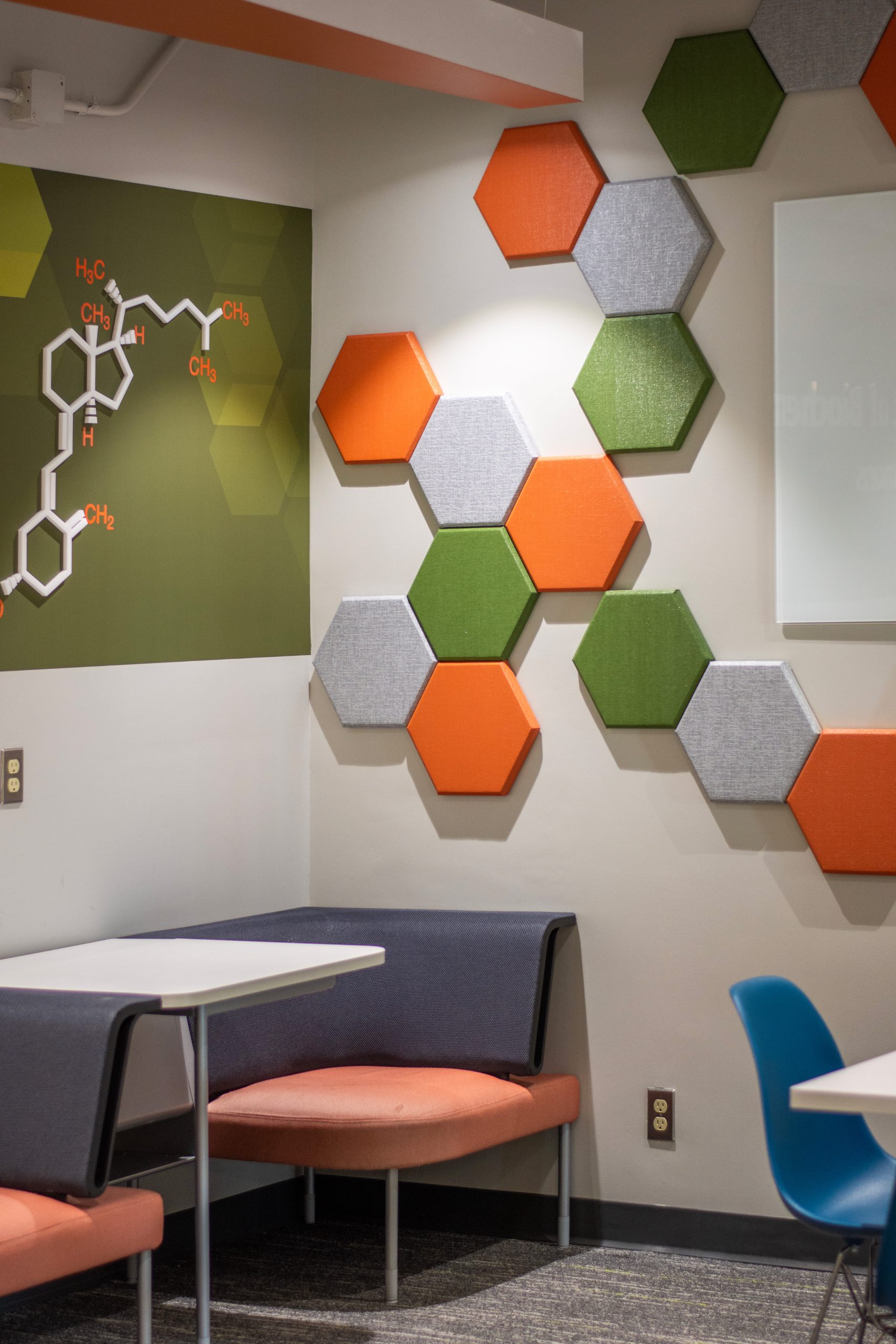 Bold orange, green, and gray textured hex wall audio clouds and booth seating.