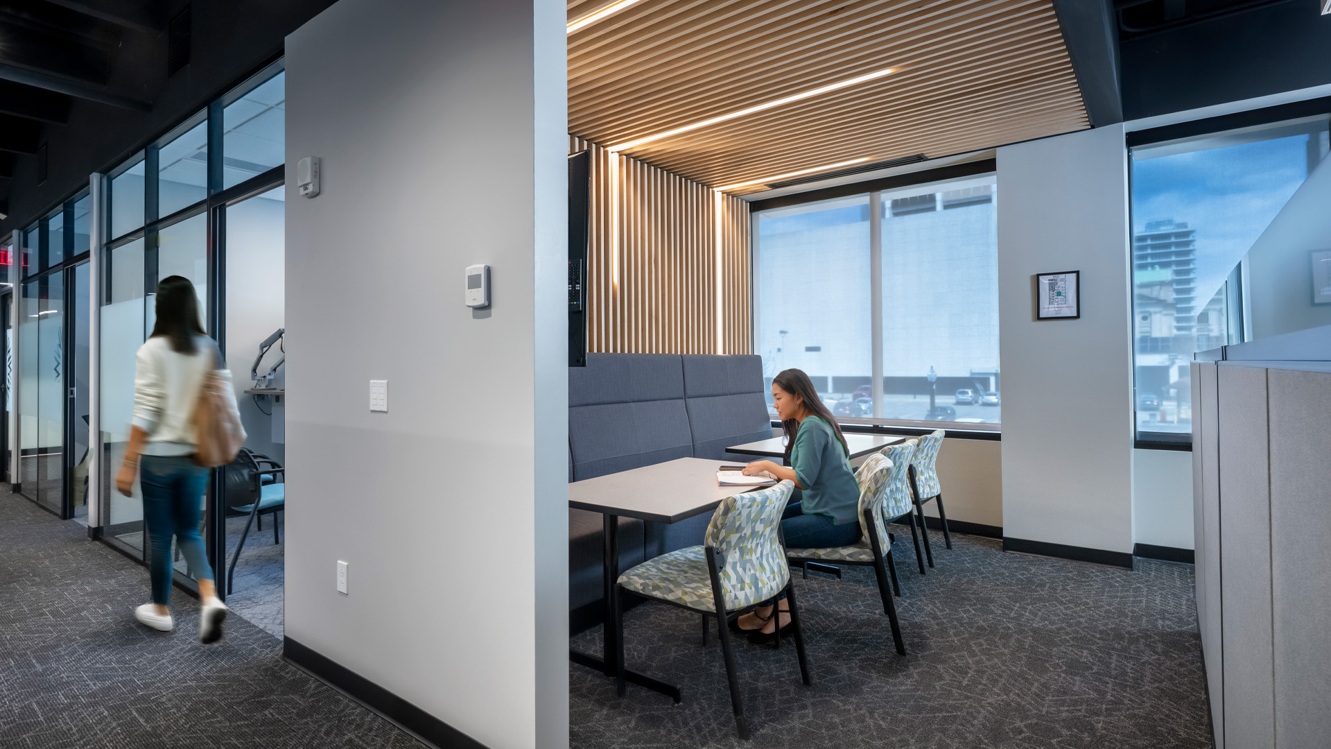 Greenway Bank collaborative workspace and hallway with one girl working and another walking past.