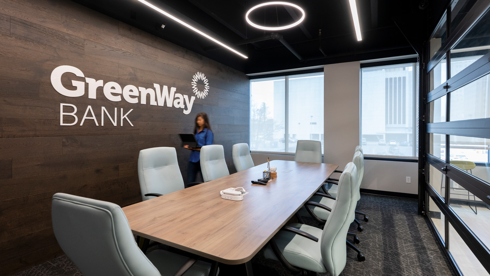 Large conference room in Greenway Bank with the Greenway Bank logo over wood paneling on the walls.