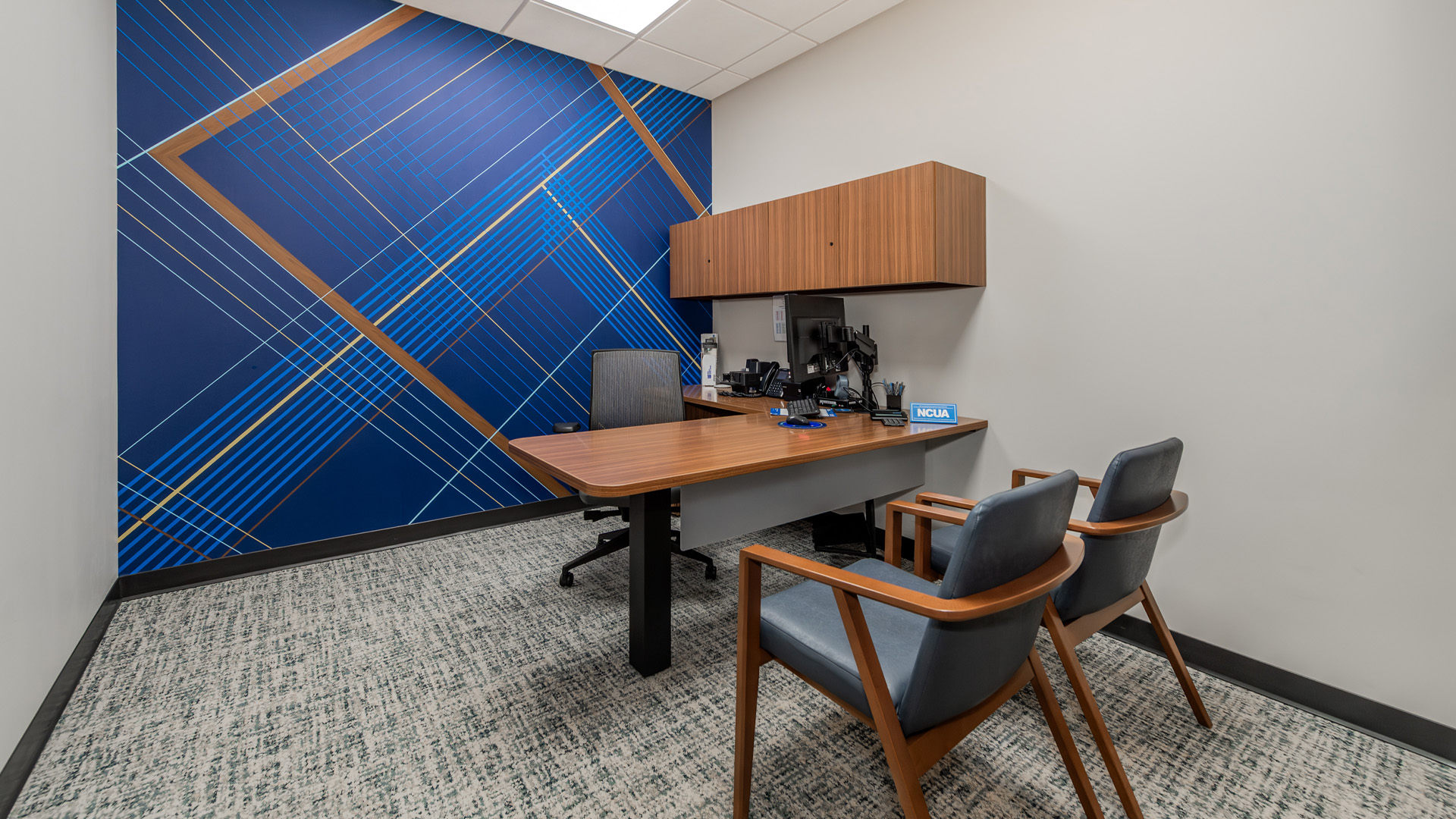 ORNL Federal Credit Union lobby private office with wood furniture and a branded graphic design wall.