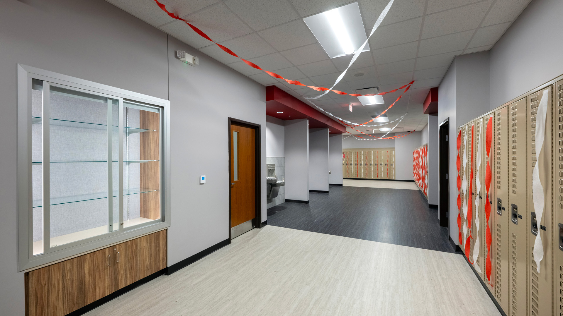A hallway at Adams Central 400 Wing Addition with beige lockers and red ceiling accents.