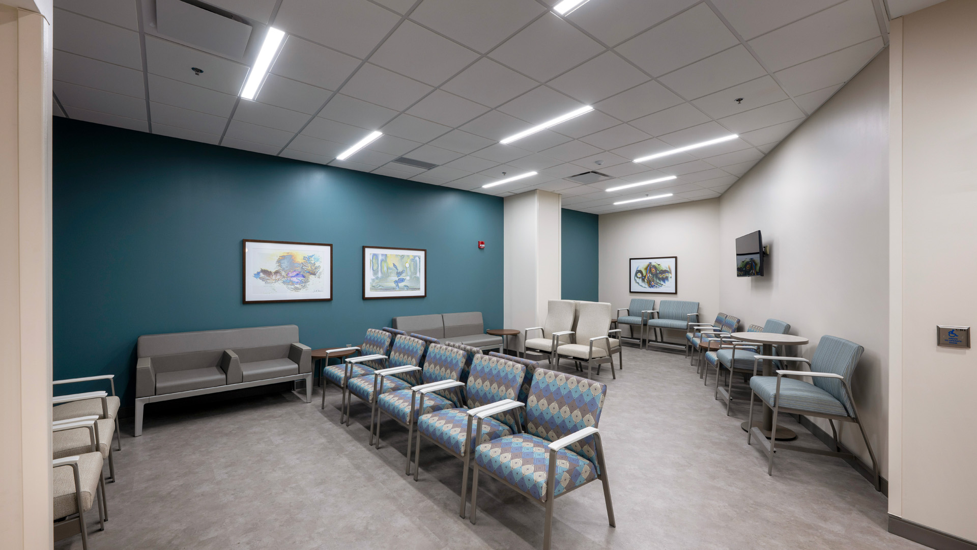 Waiting room with patterned chairs, artwork, and teal wall at Parkview Physicians Group Internal Medicine Graduate Medical Education Clinic.