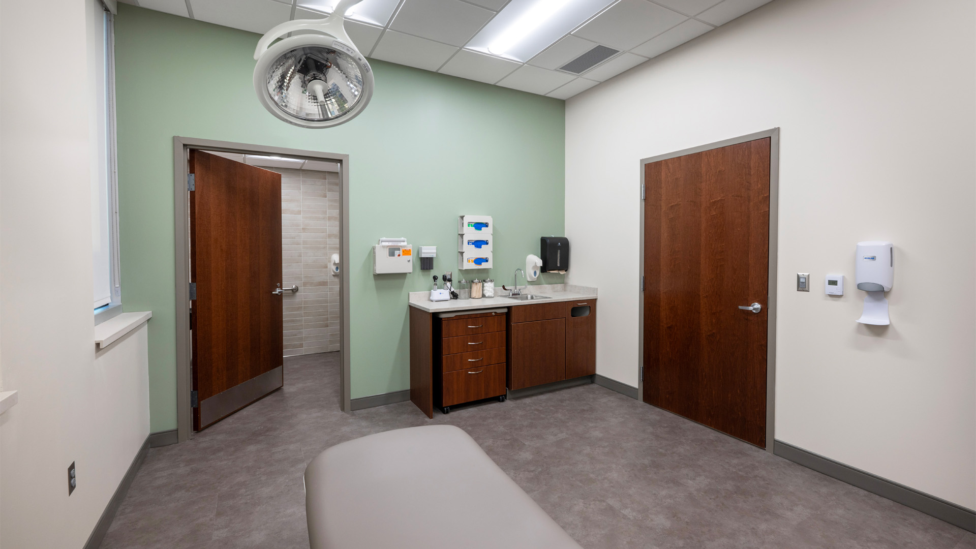 Patient room with wood doors and a teal wall at Parkview Physicians Group Internal Medicine Graduate Medical Education Clinic.