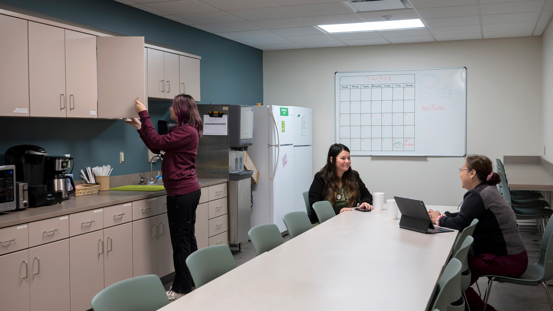 Co workers enjoying a break in a break room with plenty of cabinets at the Parkview Physicians Group Scott Road Clinic.