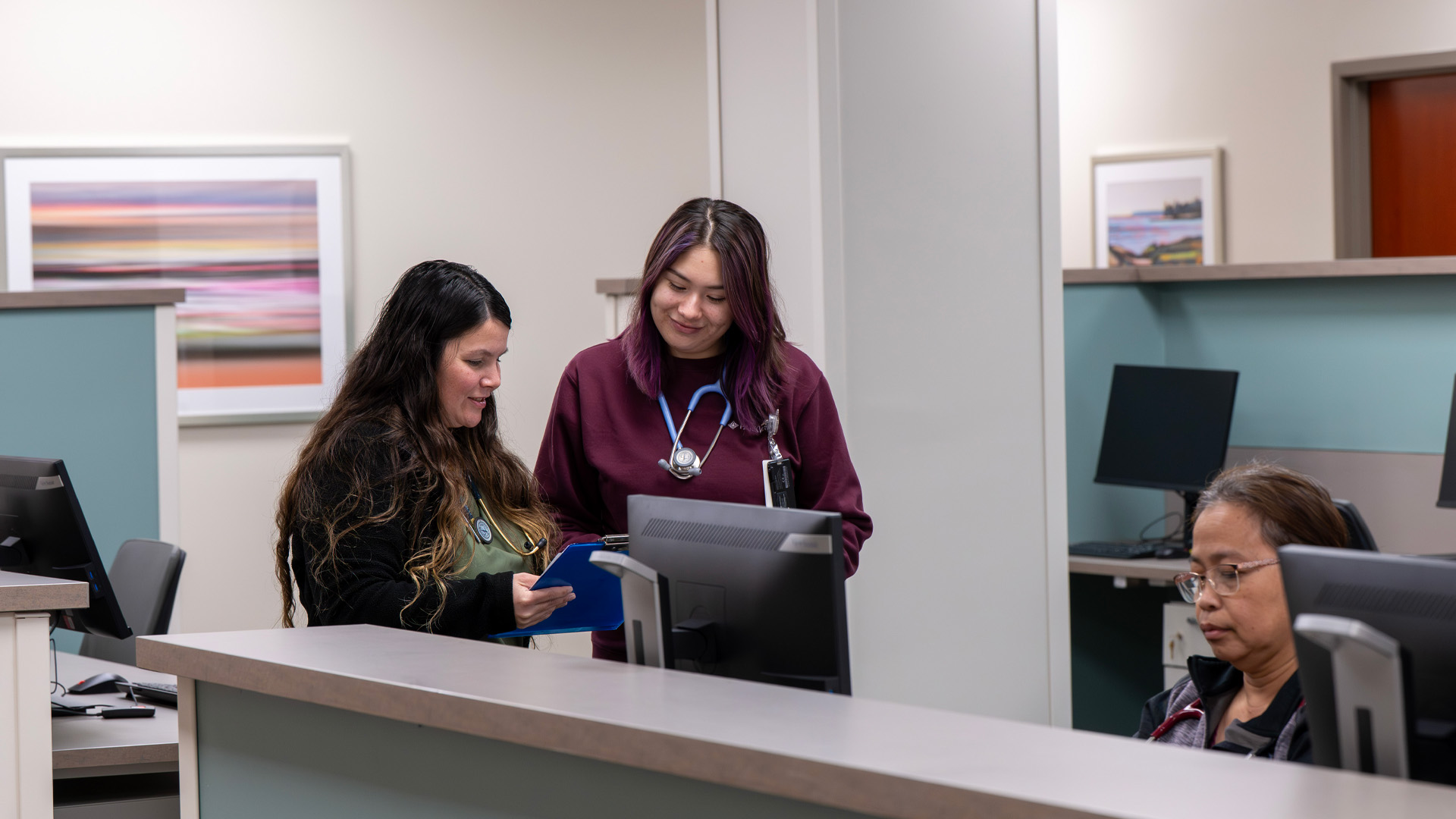 Nurses review a clipboard and work on a computer in nurses station at Parkview Physicians Group Scott Road Clinic.