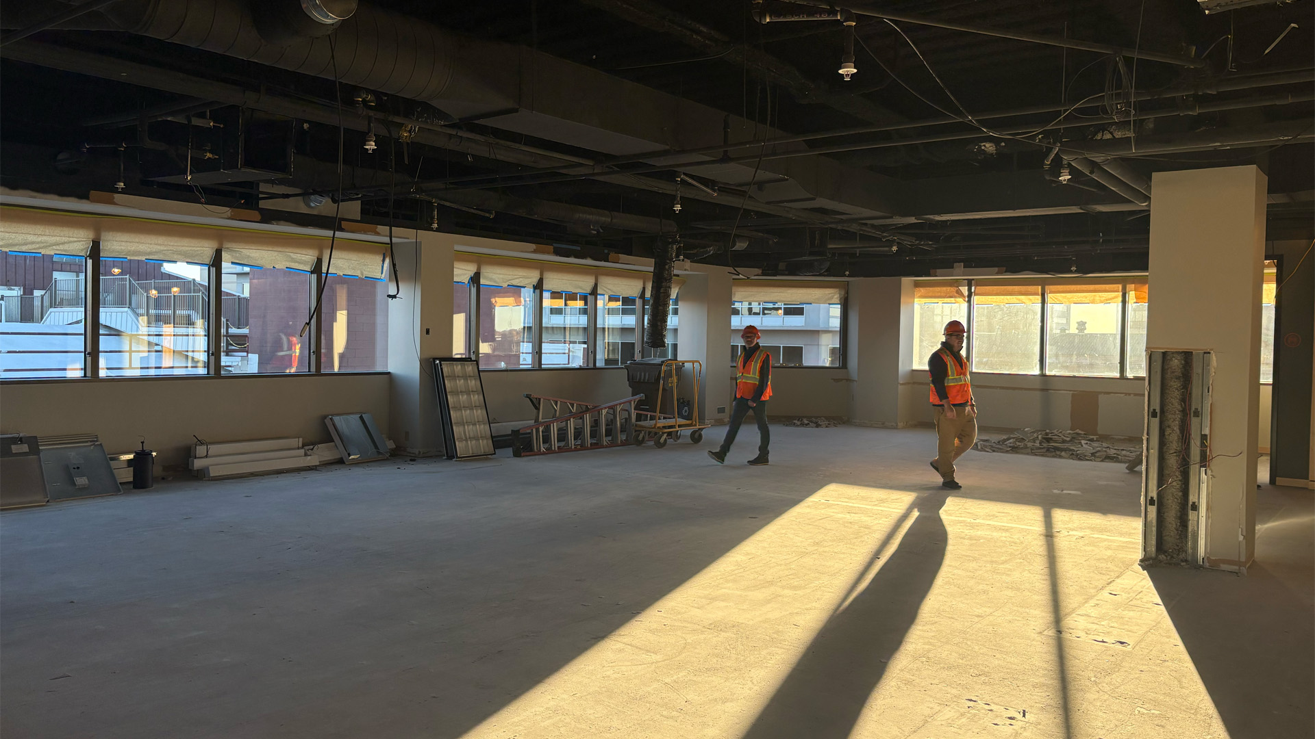 Two Design Collaborative employees walk through construction site of new office space.