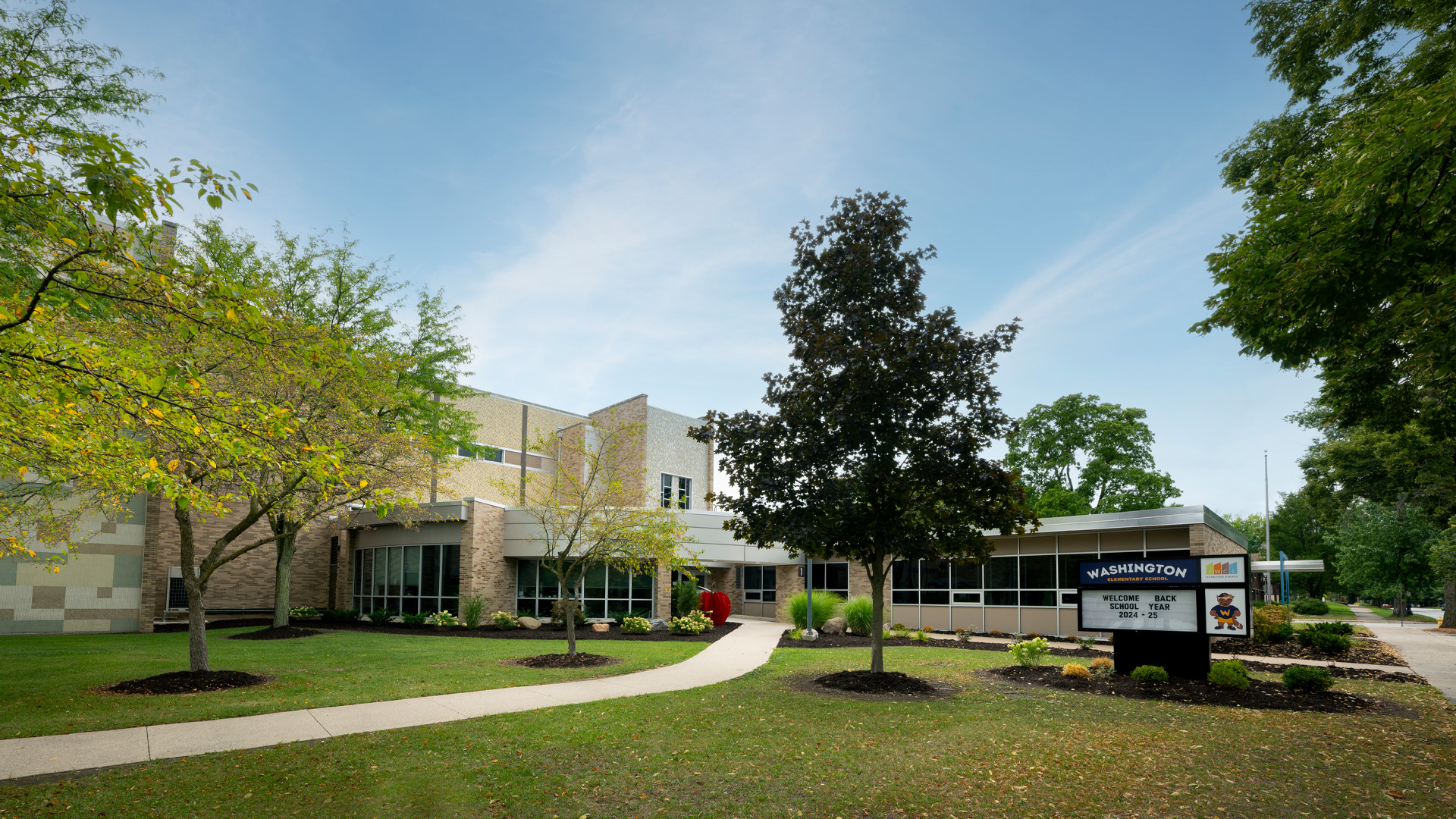 Exterior of the Fort Wayne Community Schools Washington Elementary building with trees and bright green grass in front of the entry.