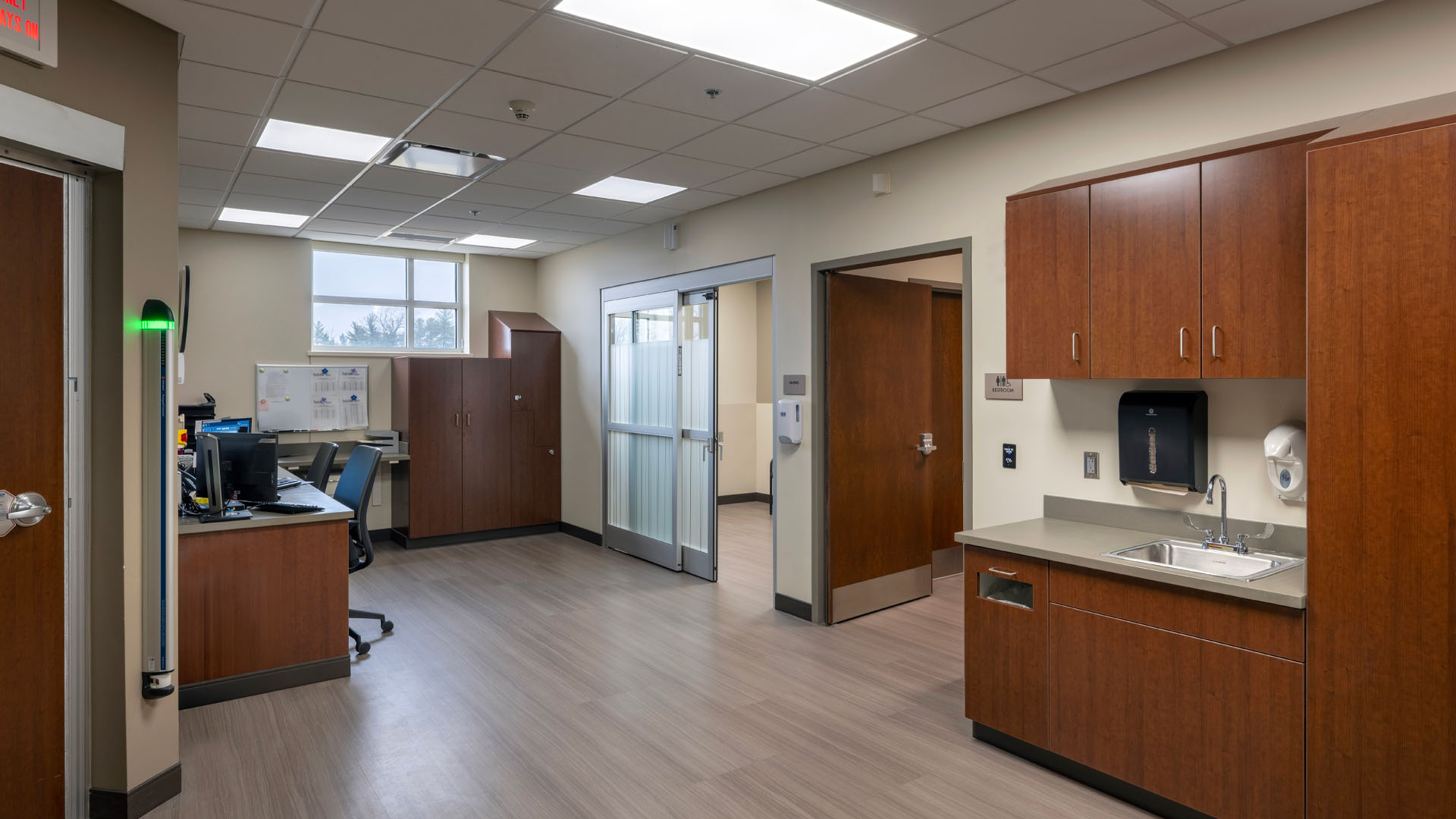 Hallway at Parkview Huntington Hospital with privacy glass sliding doors, and wood cabinets.