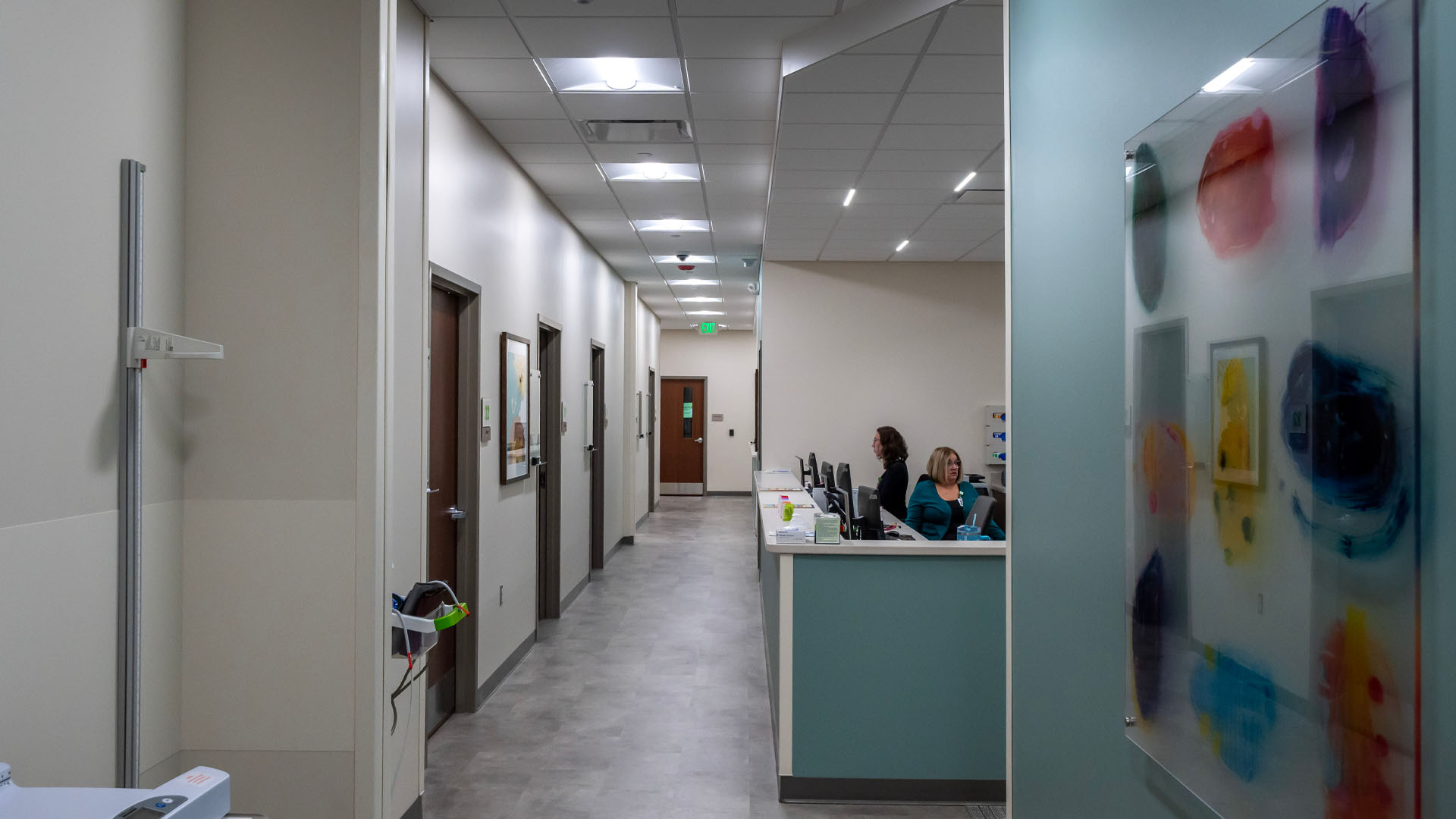 Nurses work at open nurses station with blue accents along a hallway at Parkview Physicians Group Marion Clinic with unique artwork on the wall.