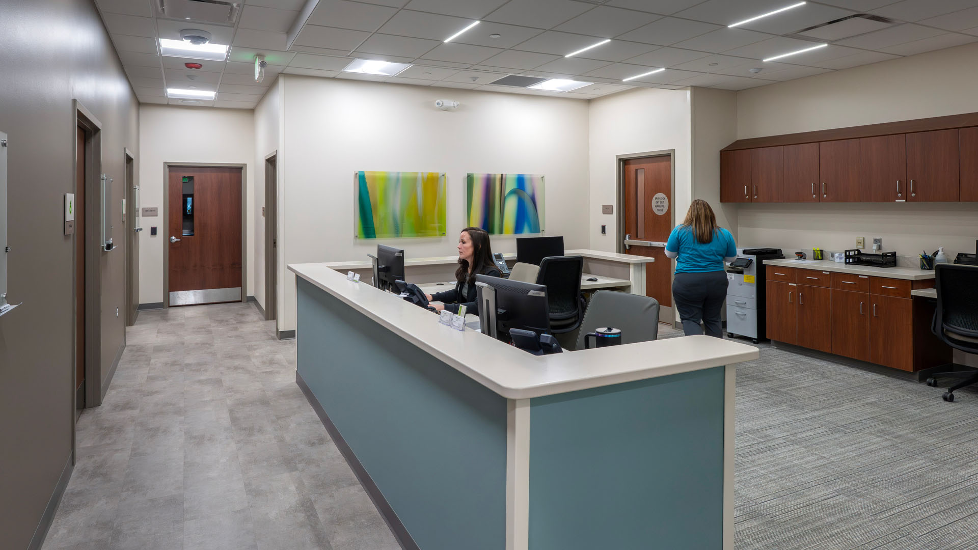 Nurses work at open nurses station with blue accents along a hallway at Parkview Physicians Group Marion Clinic with unique artwork on the wall.