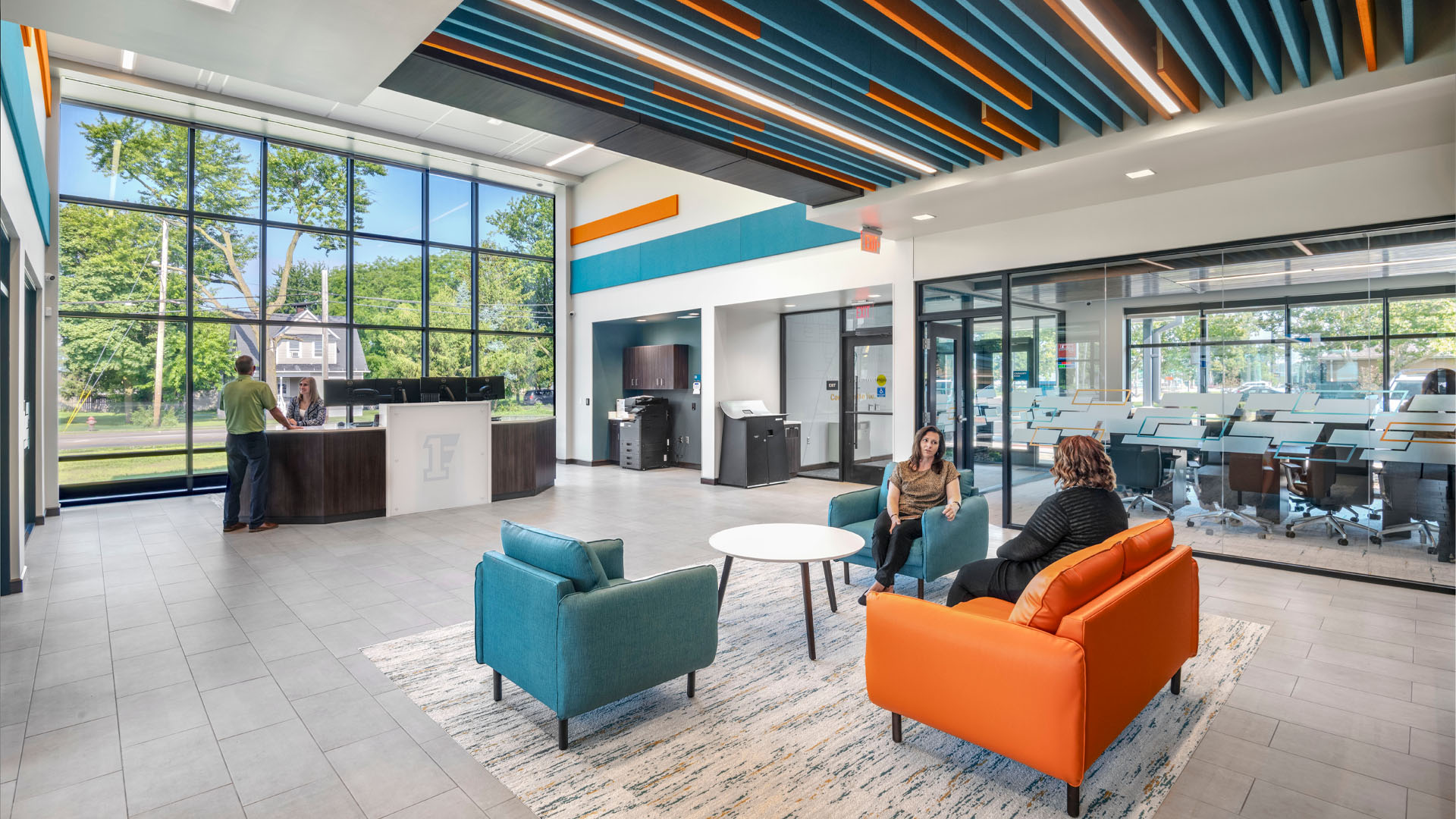 Teller line in First Federal Bank Van Wert Branch with bright orange and blue branding and large windows.