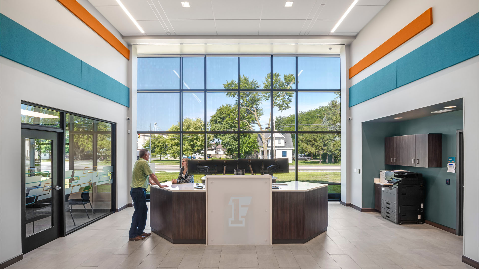 Teller line in First Federal Bank Van Wert Branch with bright orange and blue branding and large windows.