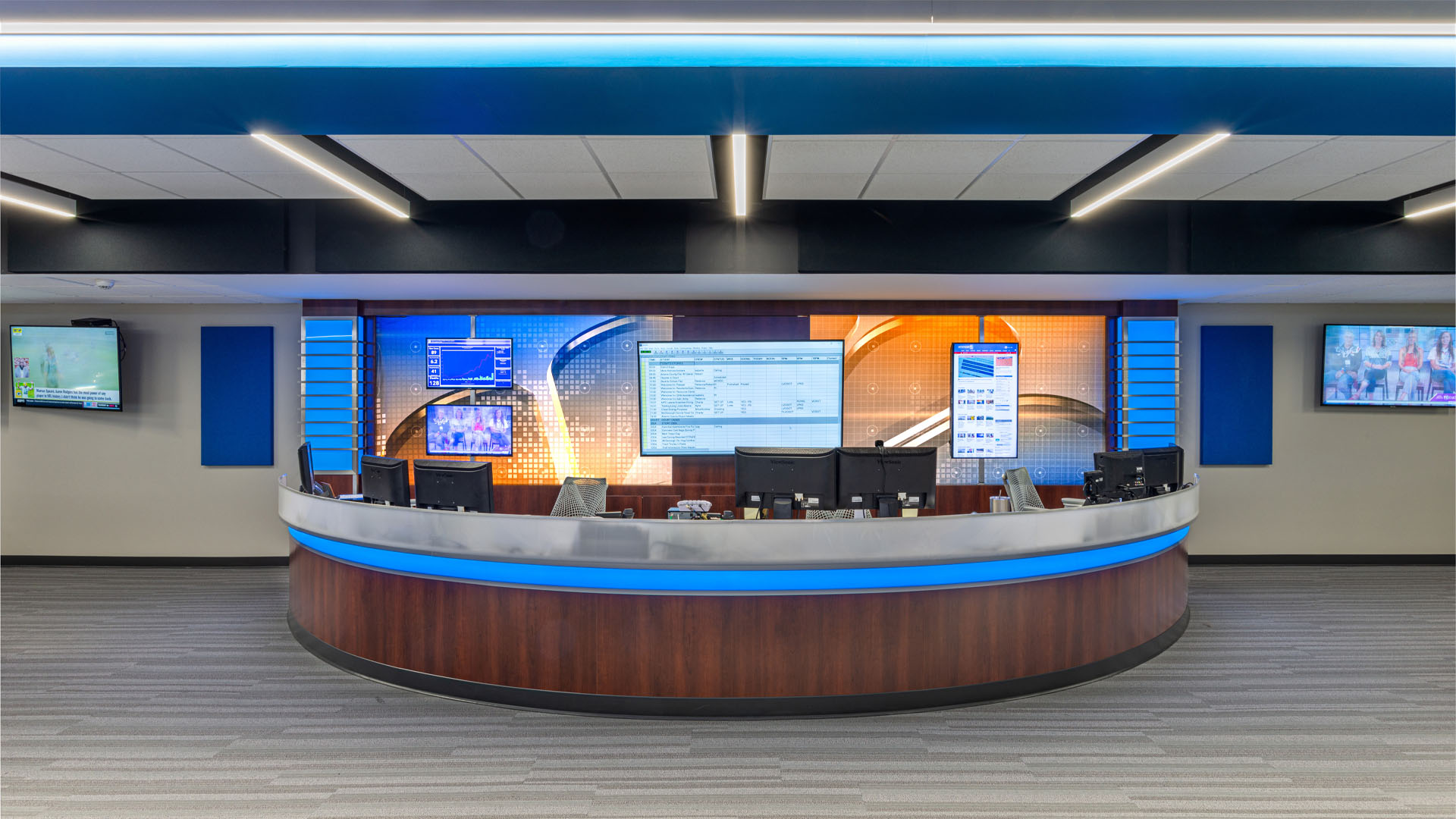 Quincy Broadcasting WGEM news studio with decorative blue accents, strong lines, media screens, and an open office layout.