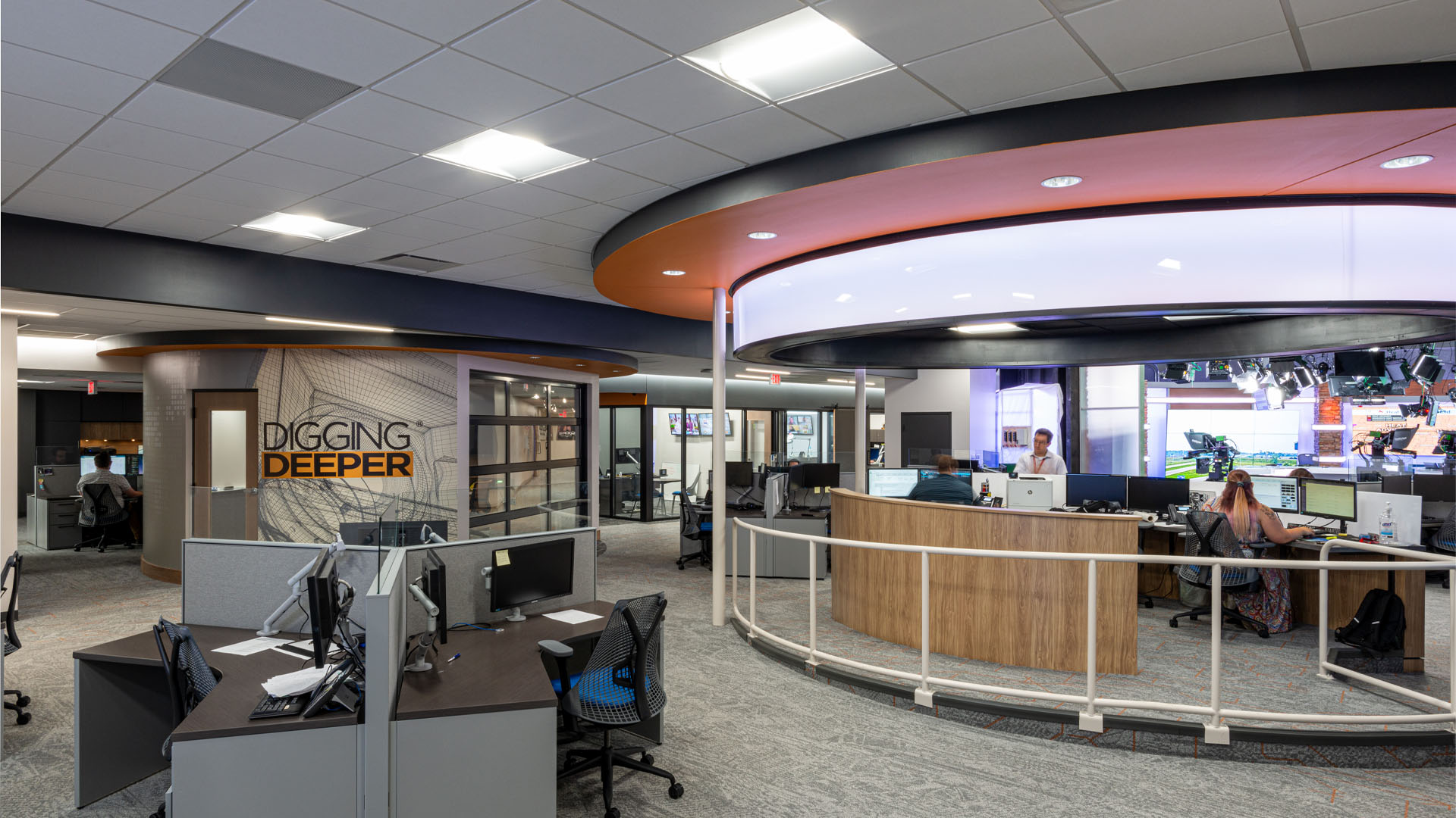 Quincy Broadcasting WSIL-TV Newsroom with colorful orange ceiling details, a graphic wall with a mission statement, and an open office layout.
