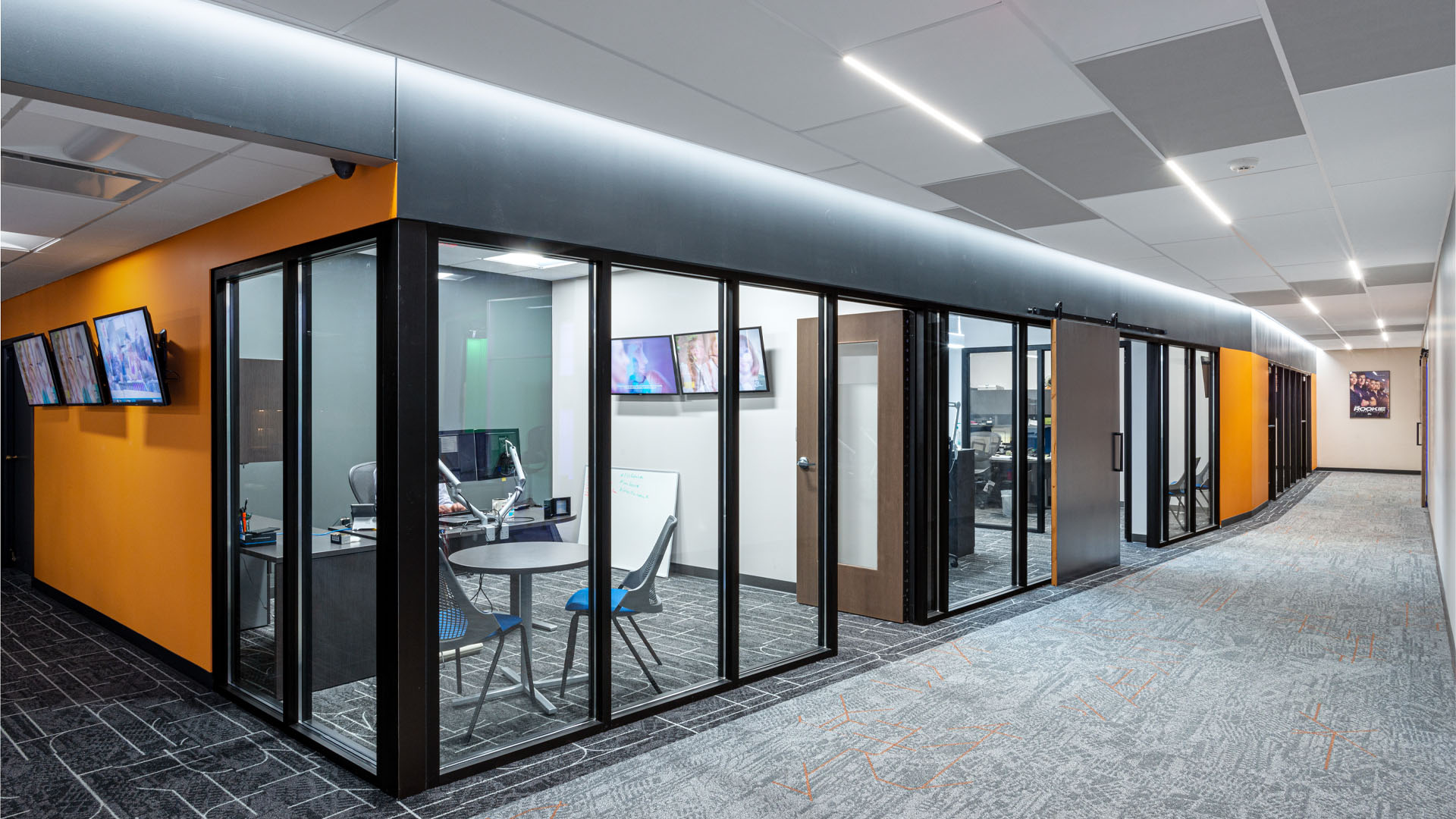 Hallway at Quincy Broadcasting WSIL-TV Newsroom with open glass windowed offices with colorful yellow accents.