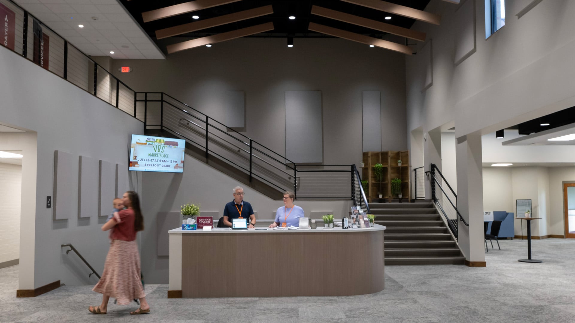 Volunteers talk while a mother and child walked past the welcome desk in the Lobby at Headwaters Church in Fort Wayne Indiana.