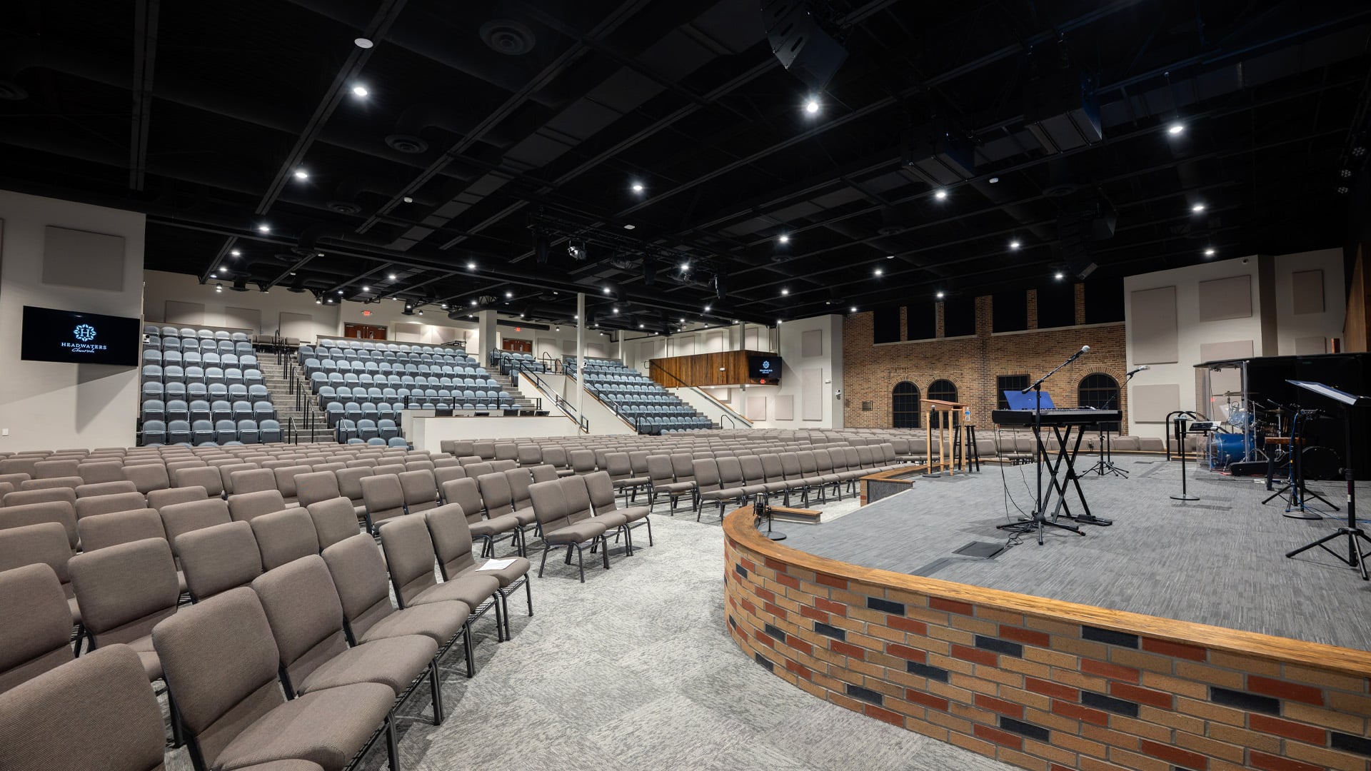 A sanctuary and auditorium stage with wood and brick accents at Headwaters Church in Fort Wayne Indiana.