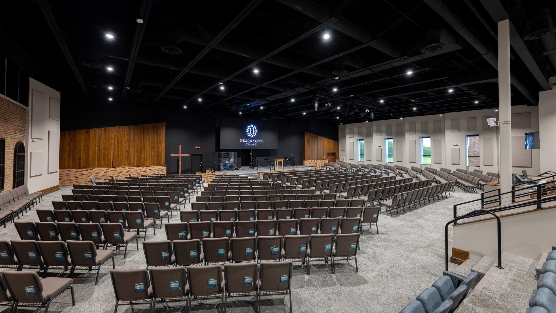 A wide sanctuary and auditorium with wood and brick accents along with windows lining the space at Headwaters Church in Fort Wayne Indiana.
